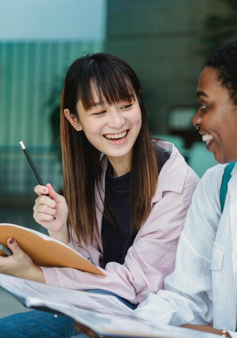 Two women smiling and discussing notes.
