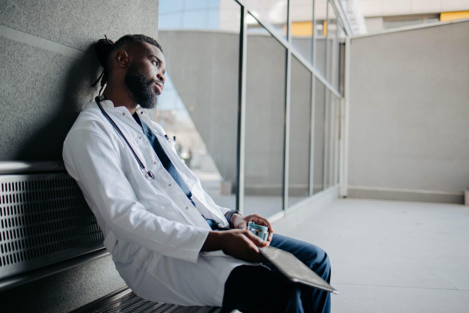 Tired doctor sitting on bench holding coffee