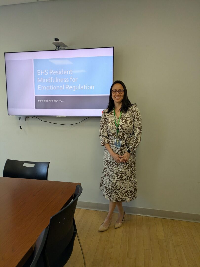 Woman standing beside mindfulness presentation on screen